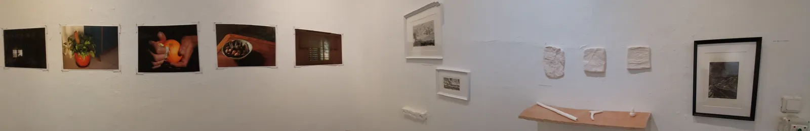 מבט פנורמי בחלל התערוכה: שורת צילומים ויצירות נוספות על הקירות